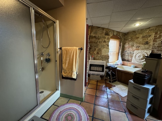 bathroom with heating unit, a paneled ceiling, a stall shower, tile patterned flooring, and a bath