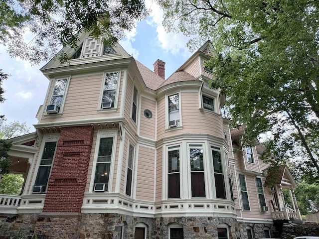 view of front facade with brick siding and a chimney