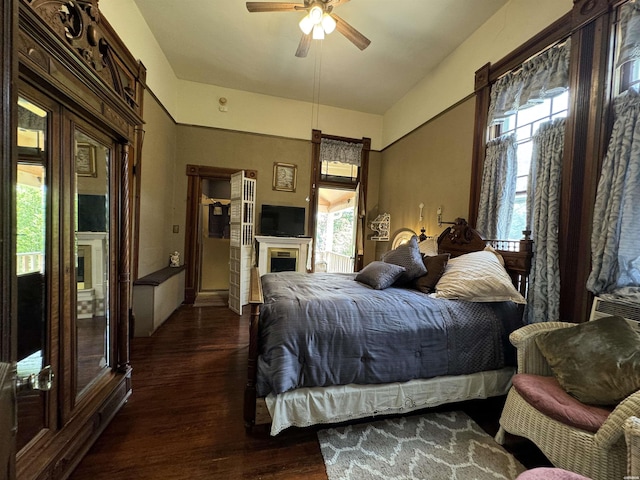 bedroom with ceiling fan, dark wood-type flooring, and a fireplace