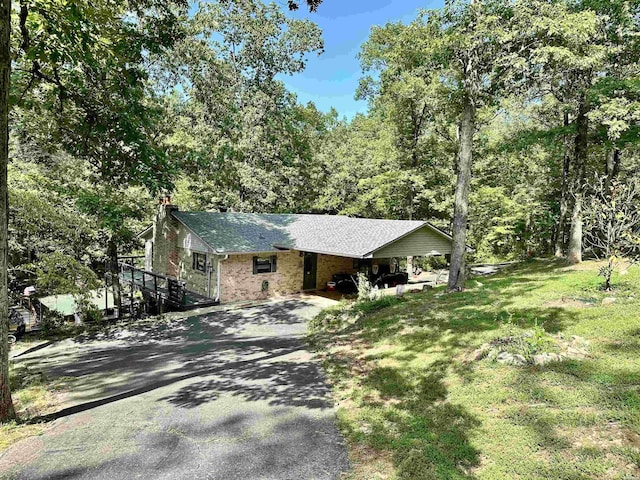 view of front of property featuring aphalt driveway, a front lawn, and brick siding