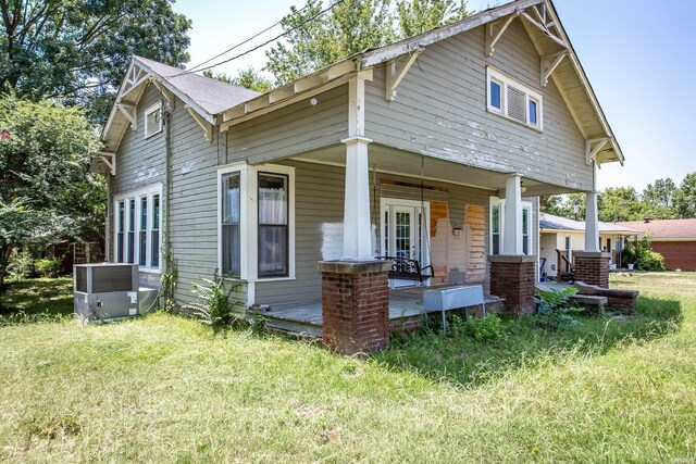 view of front of home with a porch, a front yard, and central air condition unit