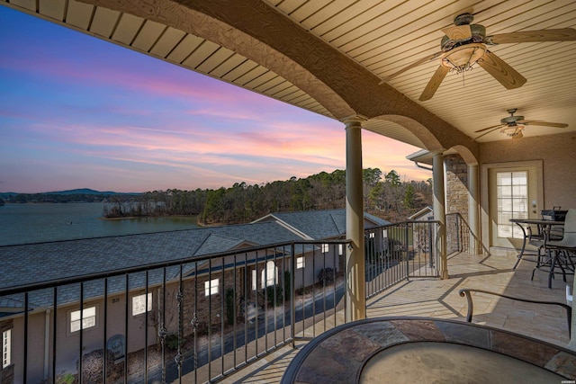 view of patio with a water view, ceiling fan, and a balcony