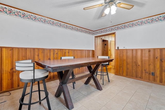 dining room featuring a wainscoted wall, a textured ceiling, and wood walls