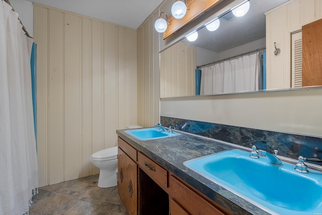 bathroom with a sink, toilet, and double vanity