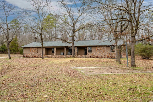 ranch-style home featuring stone siding and a front yard