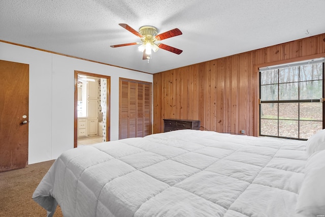 bedroom with connected bathroom, light colored carpet, ornamental molding, a textured ceiling, and wood walls