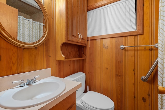 bathroom with toilet, vanity, and wooden walls