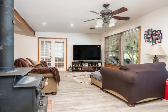 living area with light wood finished floors, a wealth of natural light, a wood stove, and a ceiling fan