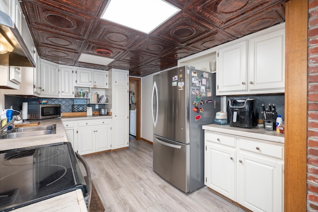 kitchen with an ornate ceiling, stainless steel appliances, light countertops, white cabinets, and a sink