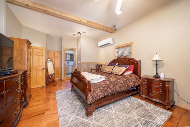 bedroom featuring baseboards, a wall mounted air conditioner, vaulted ceiling with beams, and light wood finished floors