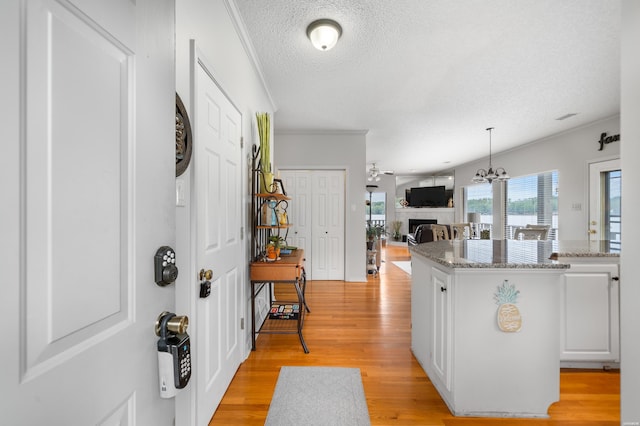 kitchen with ornamental molding, white cabinets, a fireplace, and light wood finished floors