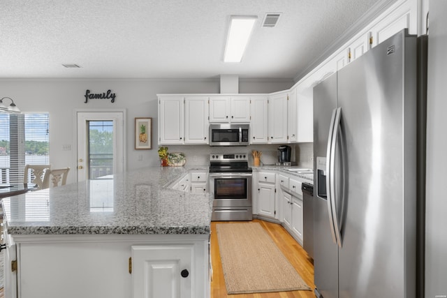 kitchen with a peninsula, white cabinetry, visible vents, and appliances with stainless steel finishes