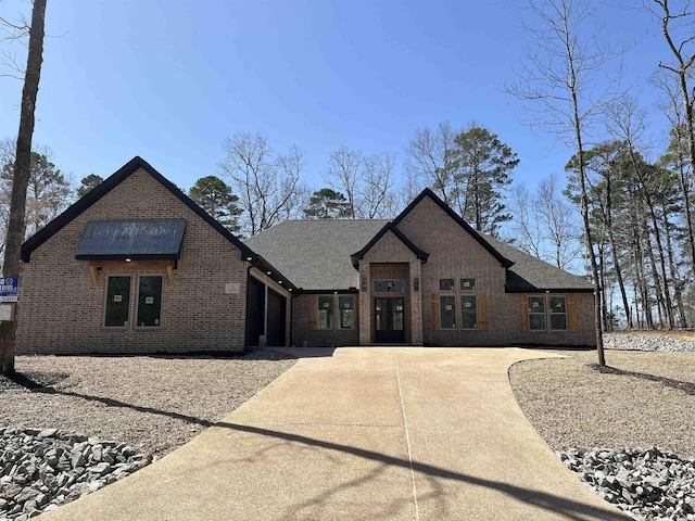 view of front of property with brick siding, an attached garage, driveway, and roof with shingles