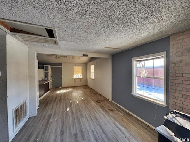 unfurnished living room featuring a textured ceiling, wood finished floors, and visible vents