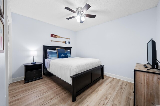 bedroom with baseboards, a textured ceiling, a ceiling fan, and light wood-style floors