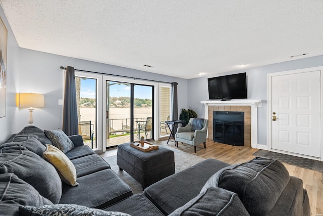 living area with a textured ceiling, a fireplace, visible vents, and wood finished floors