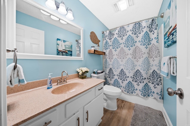 full bath with visible vents, toilet, vanity, a textured ceiling, and wood finished floors