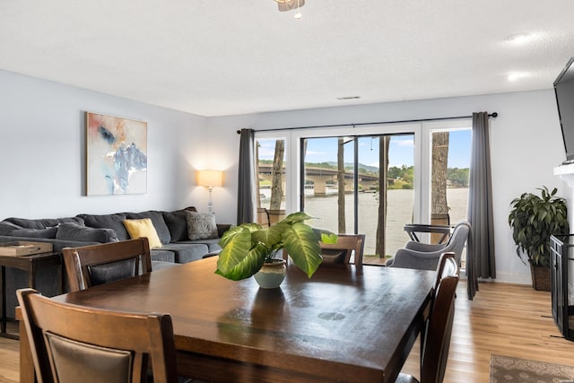 dining area featuring a fireplace, light wood-style flooring, and baseboards