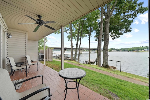 view of patio / terrace featuring a water view, ceiling fan, and fence