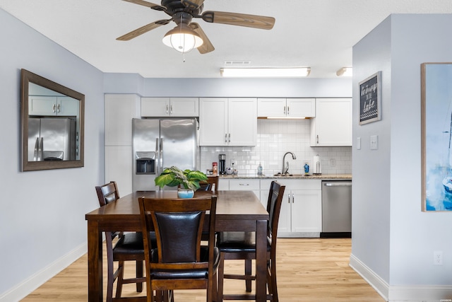 kitchen with appliances with stainless steel finishes, white cabinets, a sink, and light stone countertops