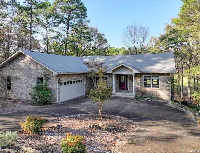 ranch-style home featuring a chimney, aphalt driveway, roof with shingles, an attached garage, and brick siding