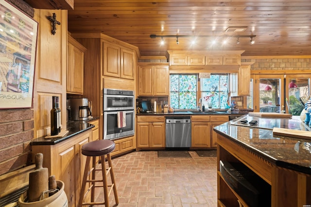 kitchen featuring brick floor, appliances with stainless steel finishes, wood ceiling, a sink, and dark stone counters