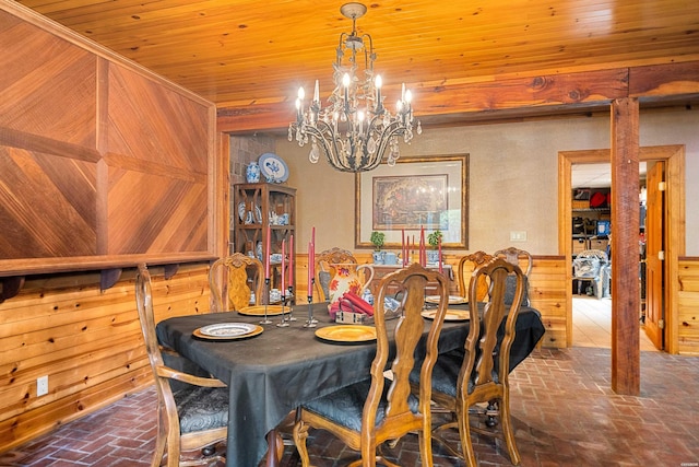 dining room featuring a chandelier, brick floor, wooden ceiling, wooden walls, and wainscoting