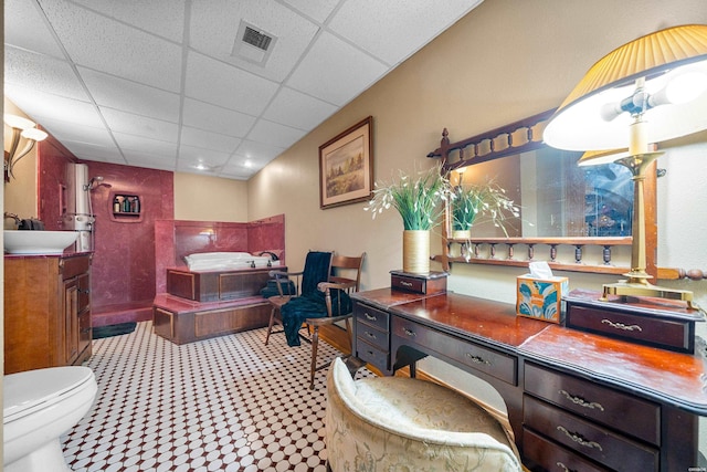 interior space featuring a drop ceiling, toilet, a washtub, vanity, and visible vents