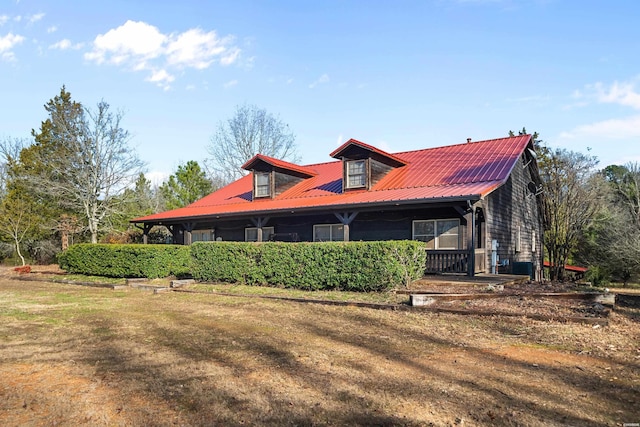 rear view of house with metal roof and a yard