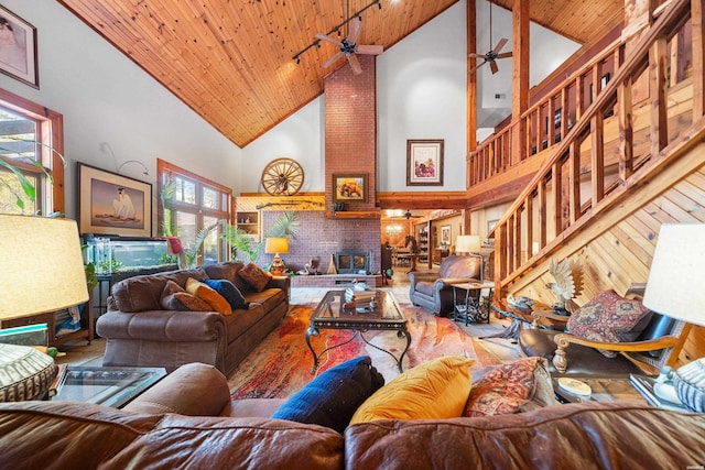 living room featuring wood ceiling, a fireplace, high vaulted ceiling, and ceiling fan