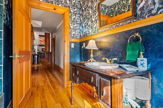 interior space featuring wallpapered walls, a sink, and wood finished floors