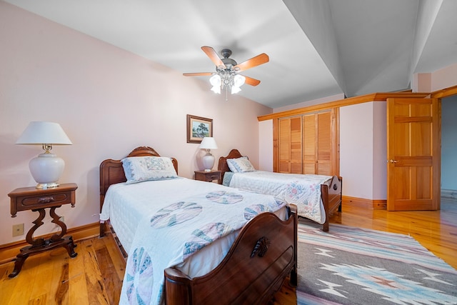 bedroom with light wood-style floors, ceiling fan, baseboards, and a closet