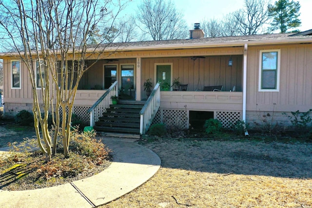 view of front of house with crawl space, stairs, a chimney, and a porch