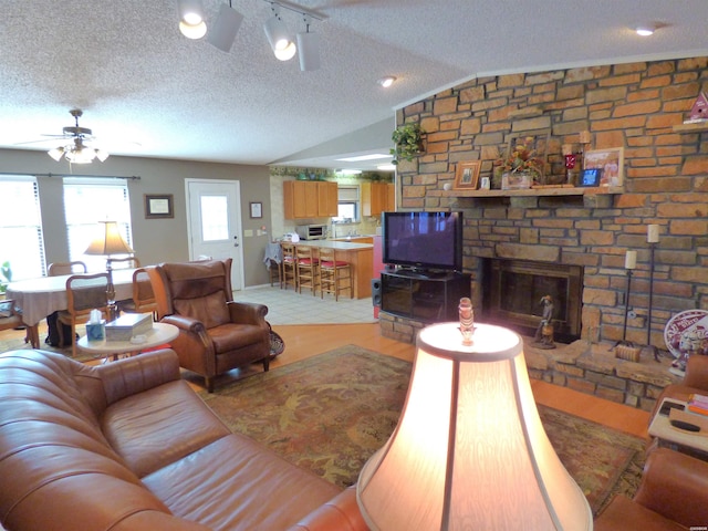 living area featuring lofted ceiling, ceiling fan, and a textured ceiling