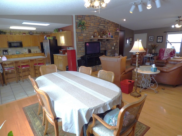 dining room with a ceiling fan, vaulted ceiling, and light wood-style flooring