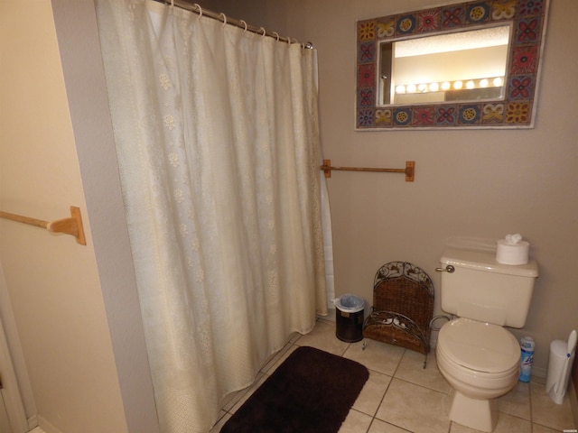 bathroom featuring toilet, curtained shower, tile patterned flooring, and baseboards