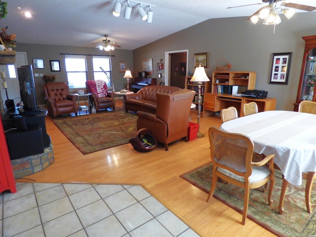 dining space with a wood stove, light wood finished floors, ceiling fan, and lofted ceiling