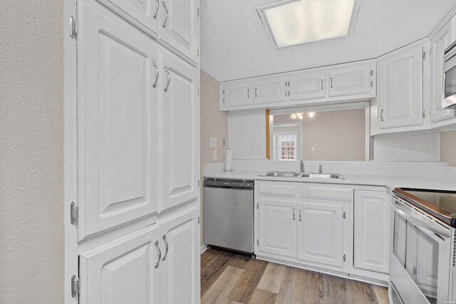 kitchen featuring white cabinets, appliances with stainless steel finishes, light countertops, light wood-style floors, and a sink