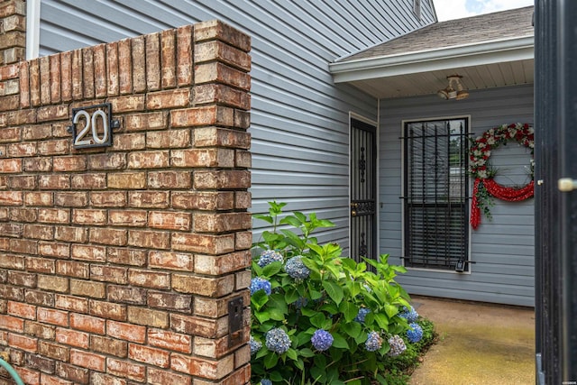 view of exterior entry with a shingled roof