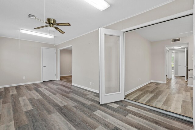 interior space with crown molding, visible vents, attic access, wood finished floors, and baseboards