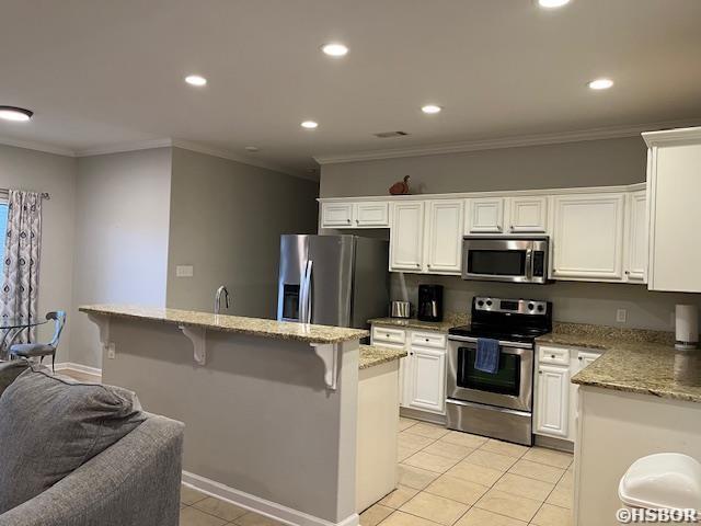 107 Legacy Ln, Hot Springs, AR 71901 - kitchen featuring light stone counters, a center island, appliances with stainless steel finishes, ornamental molding, and white cabinetry