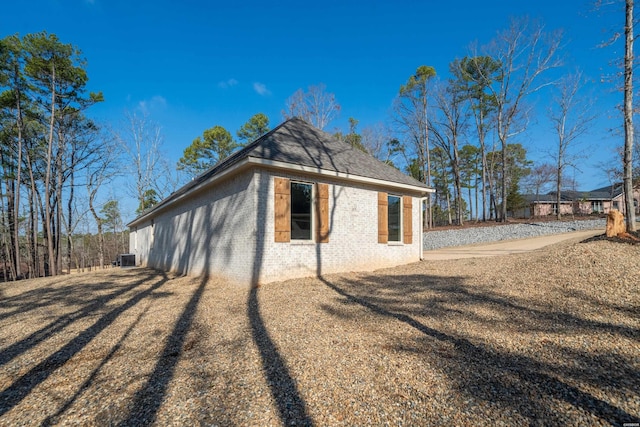 view of side of property with a yard, roof with shingles, and brick siding