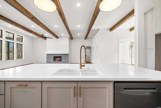 kitchen with a warm lit fireplace, a sink, open floor plan, gray cabinets, and dishwasher