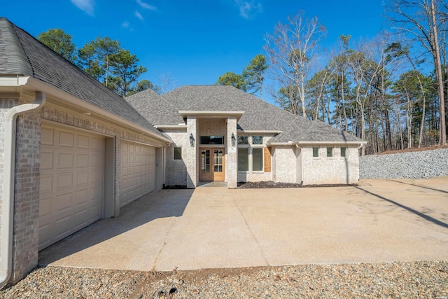 view of front of property with an attached garage, brick siding, concrete driveway, and roof with shingles