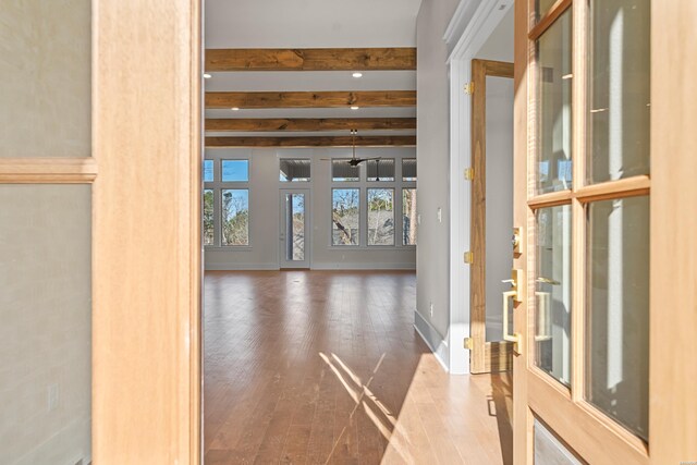 interior space with wood finished floors, beam ceiling, and baseboards