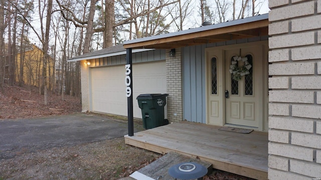 view of exterior entry with brick siding and driveway