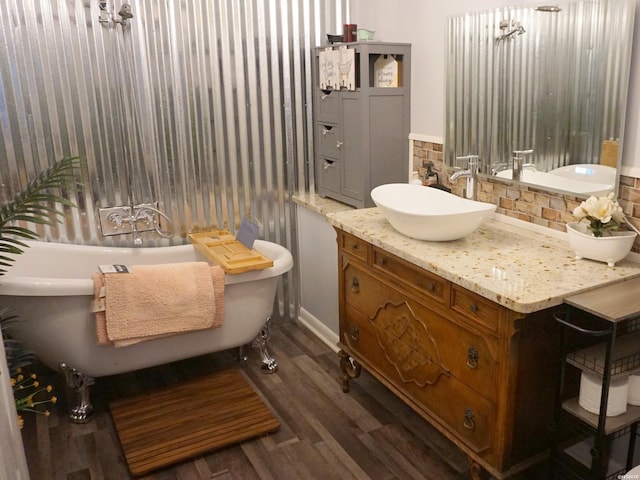 full bathroom with a freestanding tub, decorative backsplash, wood finished floors, and vanity