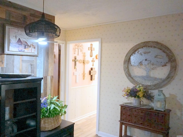 interior space featuring wallpapered walls, light wood finished floors, and ornamental molding