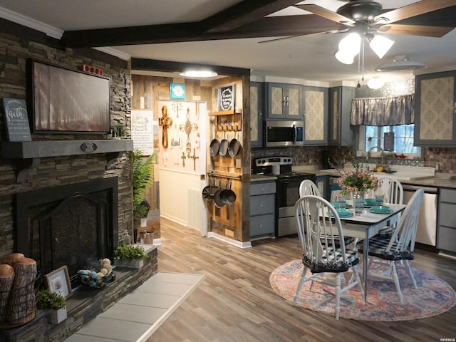 kitchen with light wood-type flooring, beam ceiling, gray cabinetry, backsplash, and stainless steel appliances