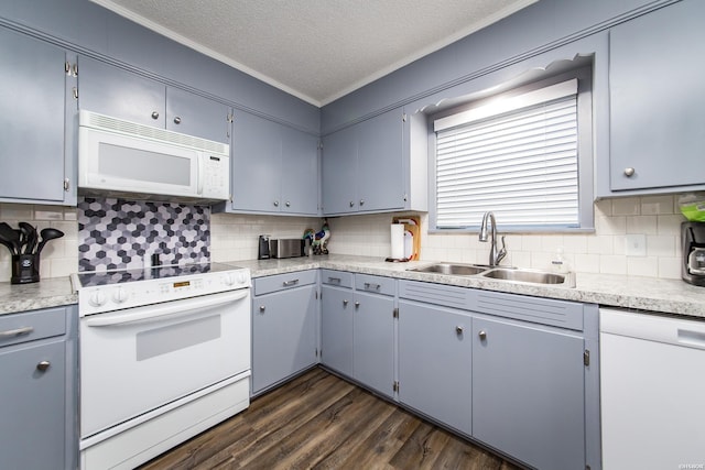 kitchen featuring a textured ceiling, white appliances, a sink, light countertops, and dark wood-style floors